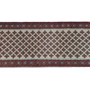 Close-up of the intricate patterns and natural dyes of the handmade Persian Baluch runner.